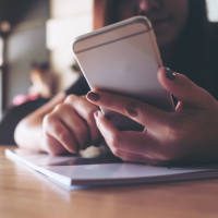 woman holding an ipad looking at analytics information and graphs surrounded by two other people looking at the data